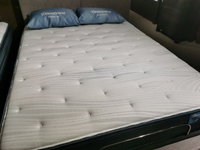 A neatly made bed showcases a Beauty-rest Anchorage TT mattress, topped with two blue pillows, promoting restorative sleep.