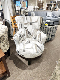 2968E Justine Swivel Chair by Best with abstract fabric on beige carpet, other swivel chairs visible in store background.