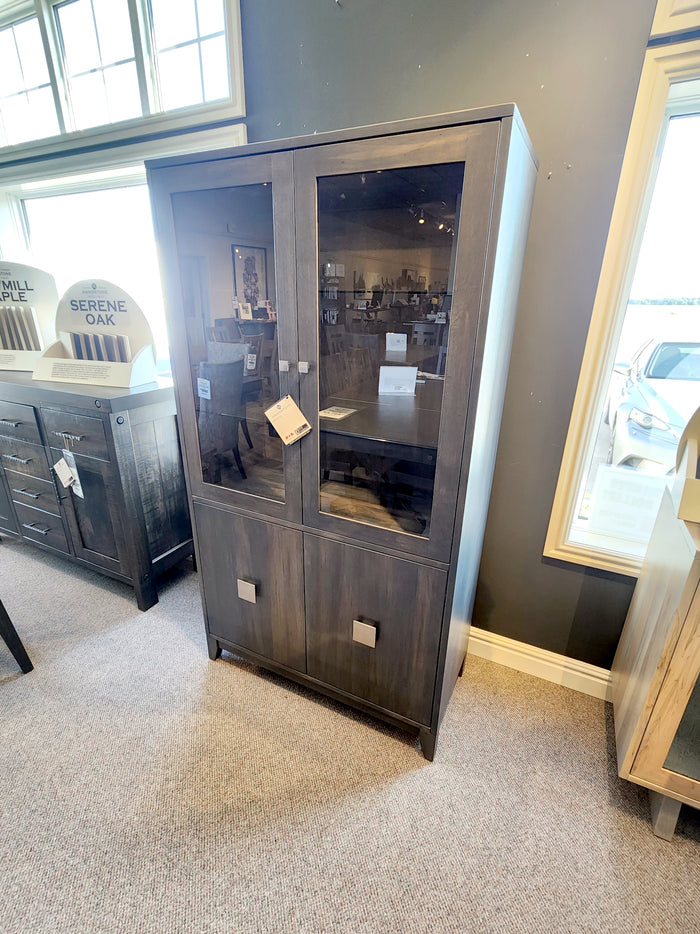 The BE270 Belmont Display Cabinet by Handstone, with glass doors, shines in showrooms with its solid dark wood design.