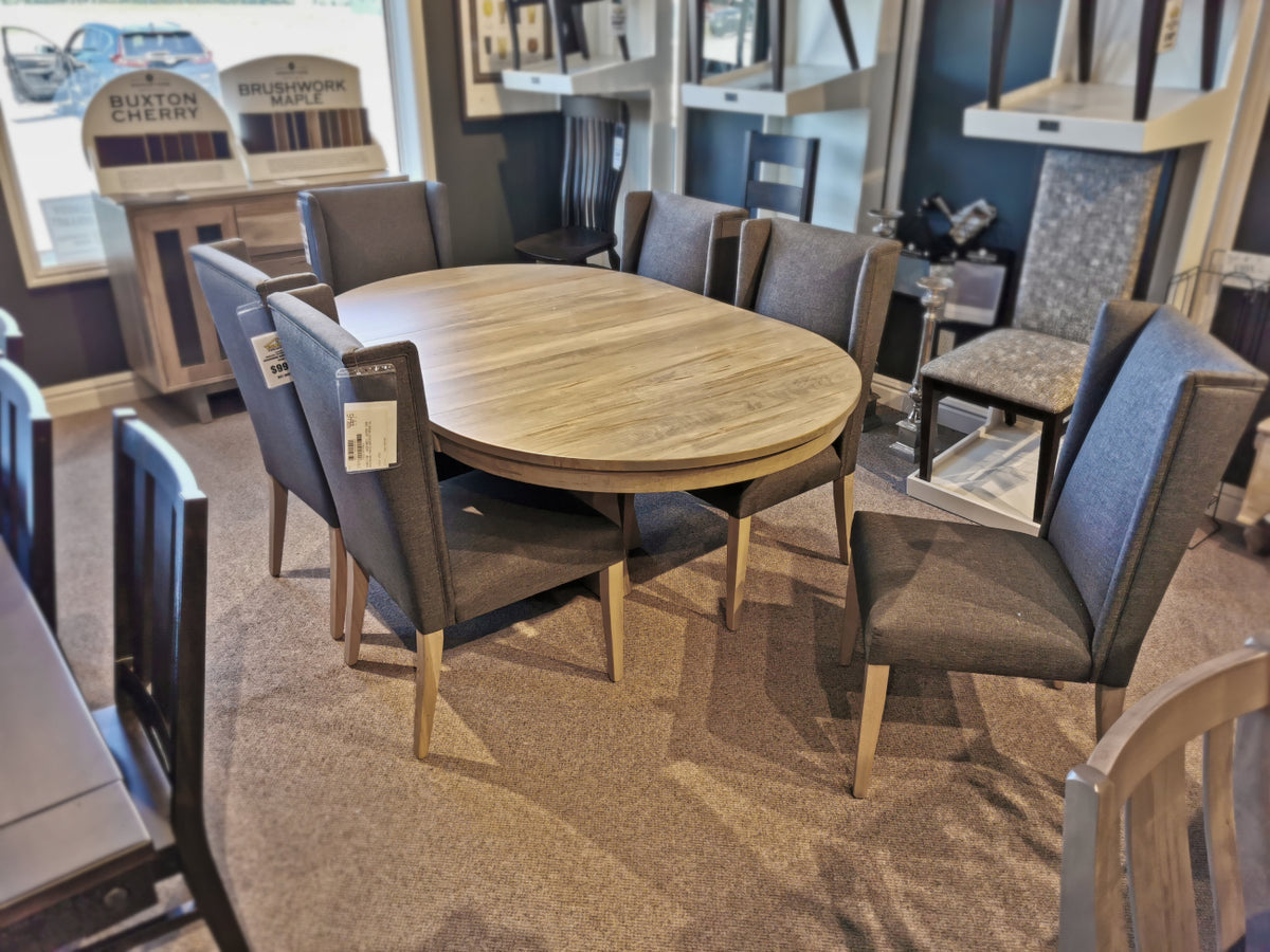 JA48 Jasper Dining Package by Handstone: oval wooden table with 6 gray chairs in a showroom.