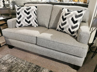 The Superstyle 9671 Loveseat in gray, casual style, with two black and white cushions in a showroom.