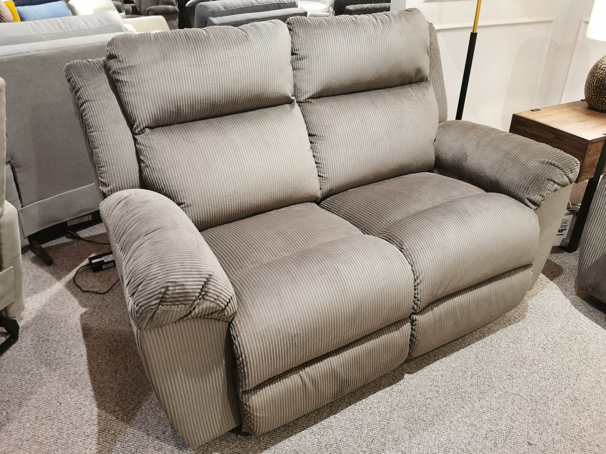 A La-z-boy 761 Joel Reclining Loveseat, featuring a gray ribbed fabric texture and cushioned arm pads, designed as a two-seater and displayed in a showroom setting.