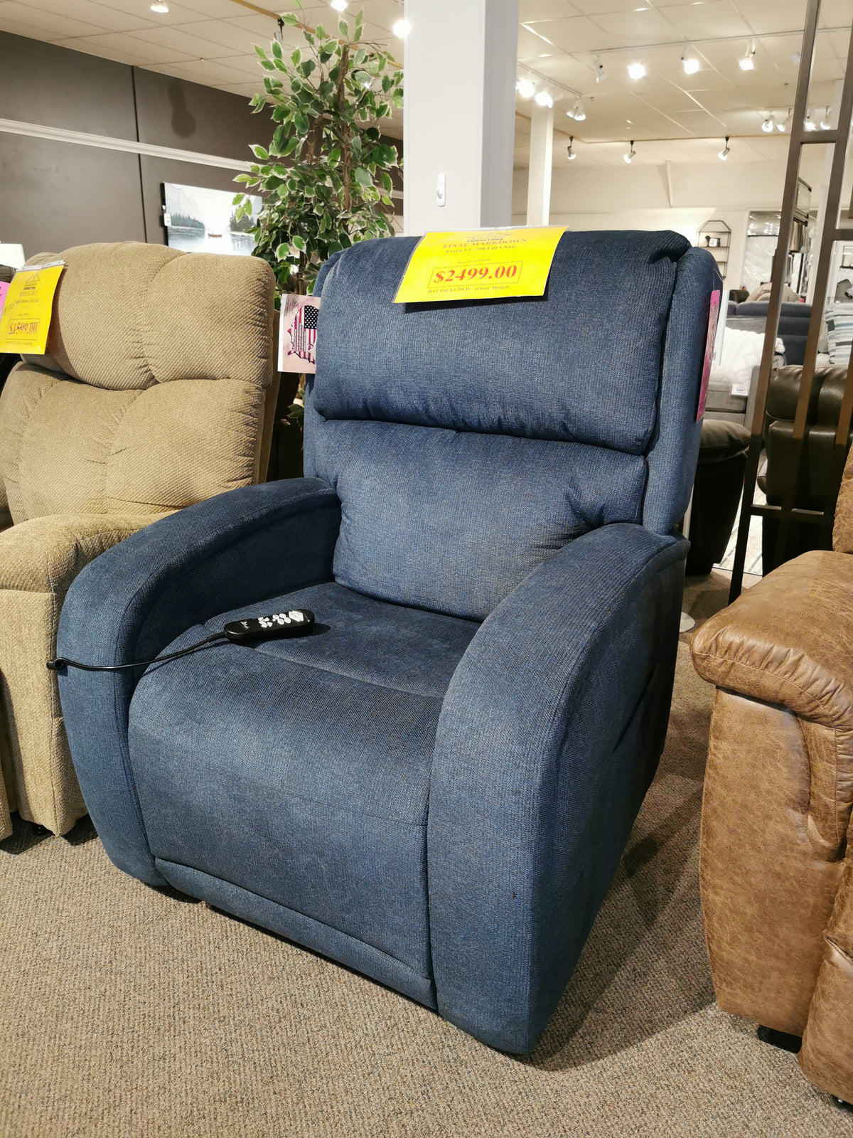 The Evren UC-798-MED Power Lift Chair by Golden, a blue upholstered recliner featuring HeatWave Technology, is on display in the furniture store showroom with a price tag of $2,499.