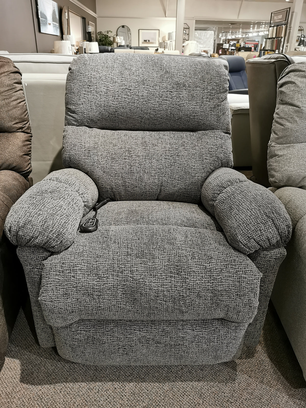 The 7MP84 Ellisport Power Space Saver Recliner by Best is displayed in a showroom, nestled among other recliners. Its sleek design and two-button remote deliver exceptional comfort.