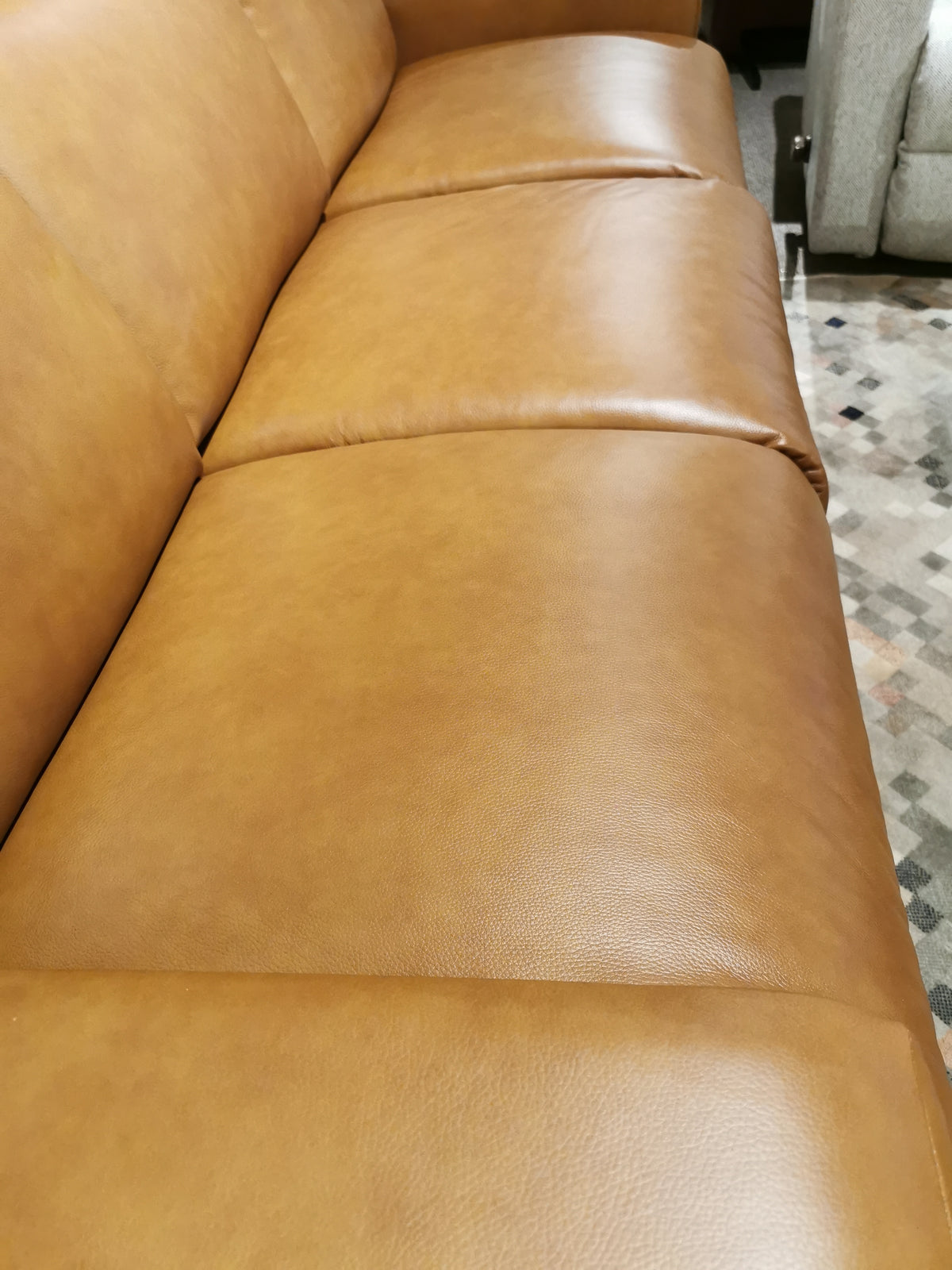 Close-up of a La-Z-Boy 781 Emmons Reclining Sofa in brown leather, featuring built-in headrests and three cushions for lumbar support, elegantly situated on a patterned rug.