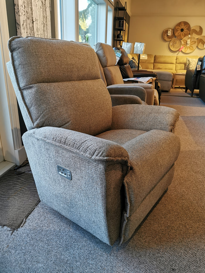 The La-Z-Boy 706 Jay Power Rocker Recliner, featuring a casual design in gray fabric, is showcased elegantly in the furniture store showroom.