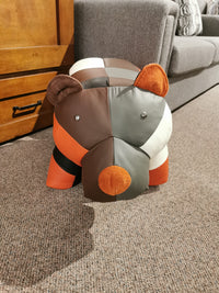 Reiner's Leather Animal Ottoman Bear by Reiner's Originals adds charm to the gray sofa on a carpeted floor.