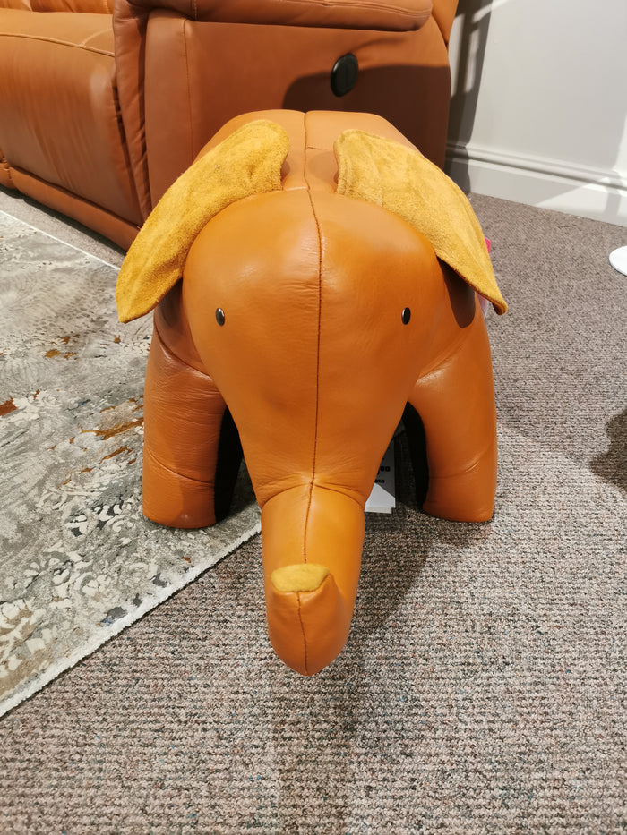 The Reiner's Originals brown leather elephant-shaped ottoman, from the Reiner's Leather Animal Ottomans collection, features cheerful yellow ears and is a delightful piece of handcrafted furniture that adds whimsy to any carpeted floor.