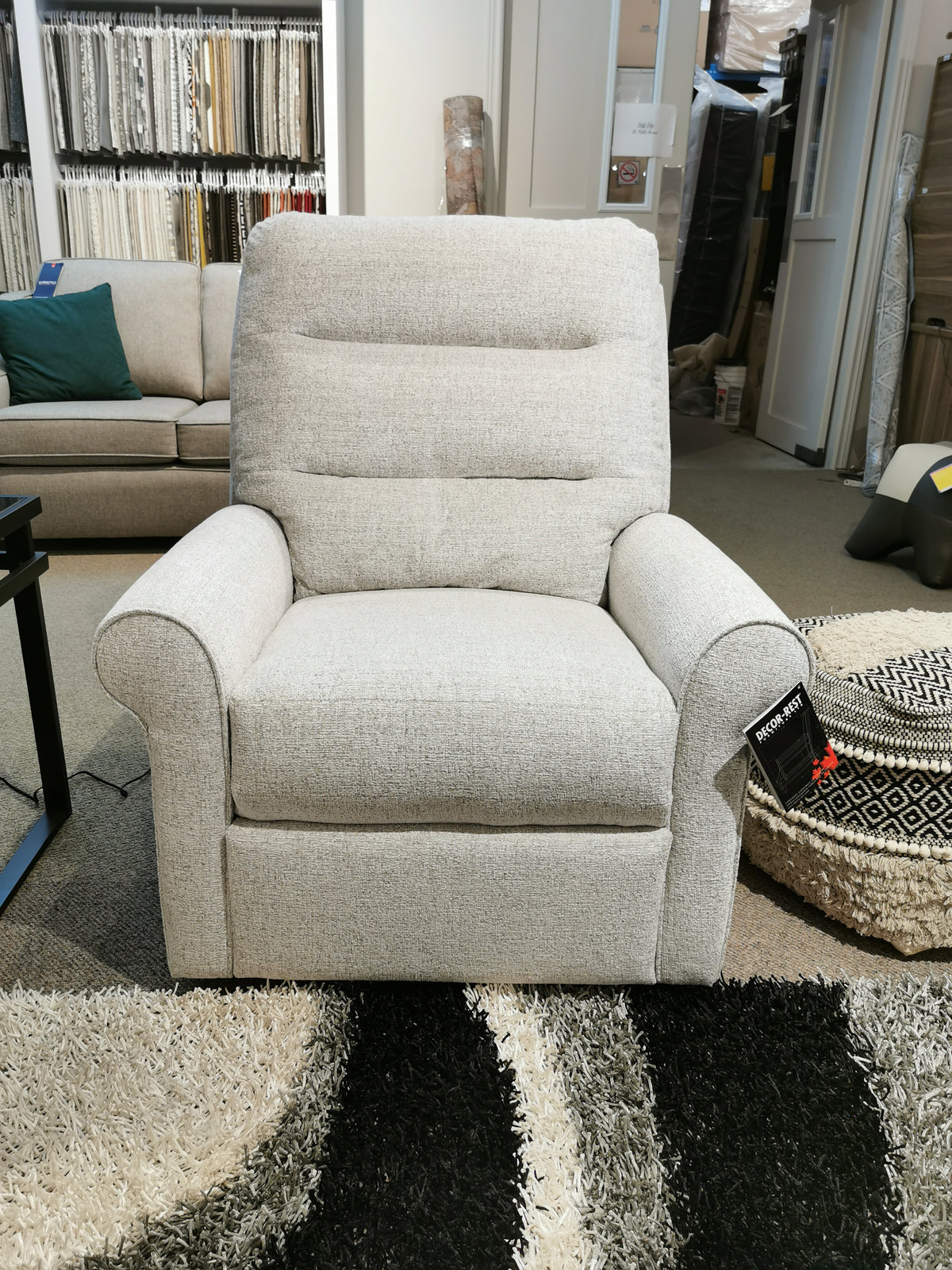 The M8508 Power Reclining Chair by Decor-rest adorns the showroom in a sophisticated gray, showcasing traditional arms and surrounded by an array of fabric swatches. This elegant piece provides headrest and lumbar support, ensuring the ultimate comfort experience.