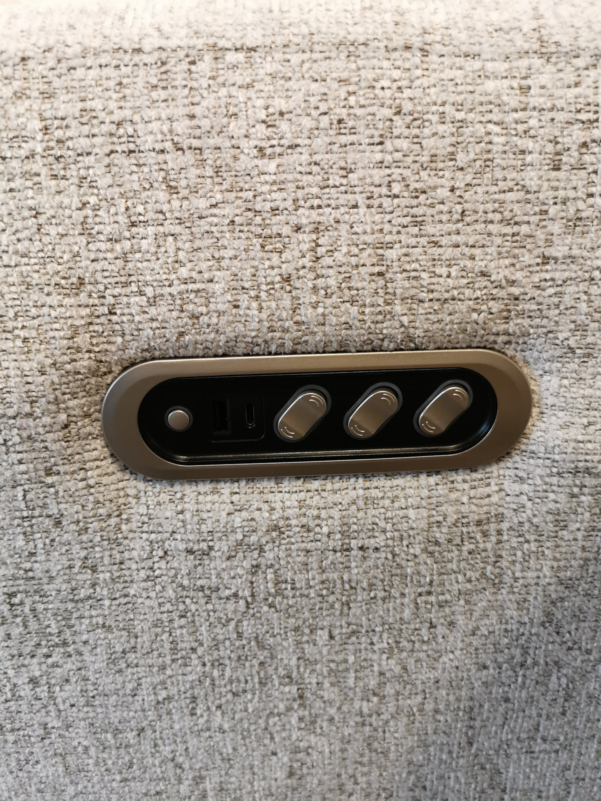 Close-up of a control panel with three buttons on the textured beige upholstery surface of the M8500 Power Reclining Chair, crafted by the renowned Canadian brand Decor-Rest.