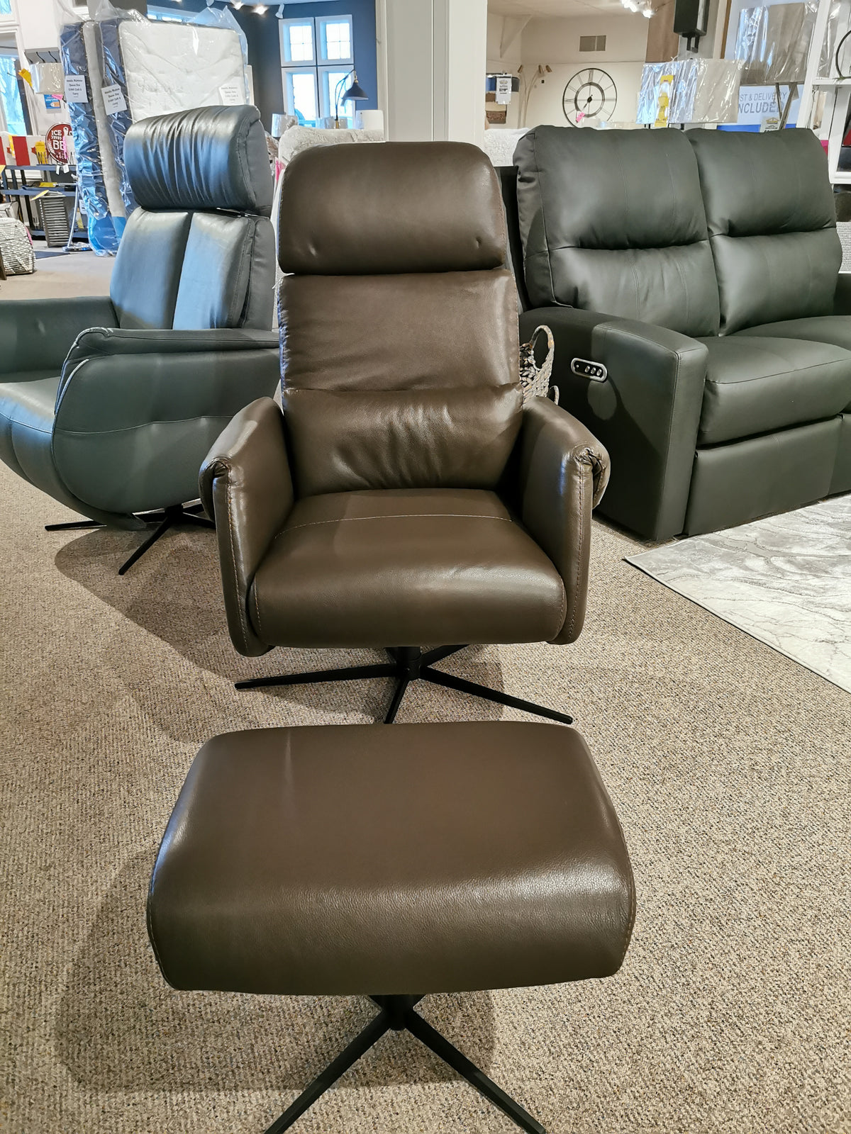 Licia Recliner with Ottoman by Donald Choi, crafted from brown Italian leather and featuring a smooth swivel mechanism, displayed in a furniture store showroom.