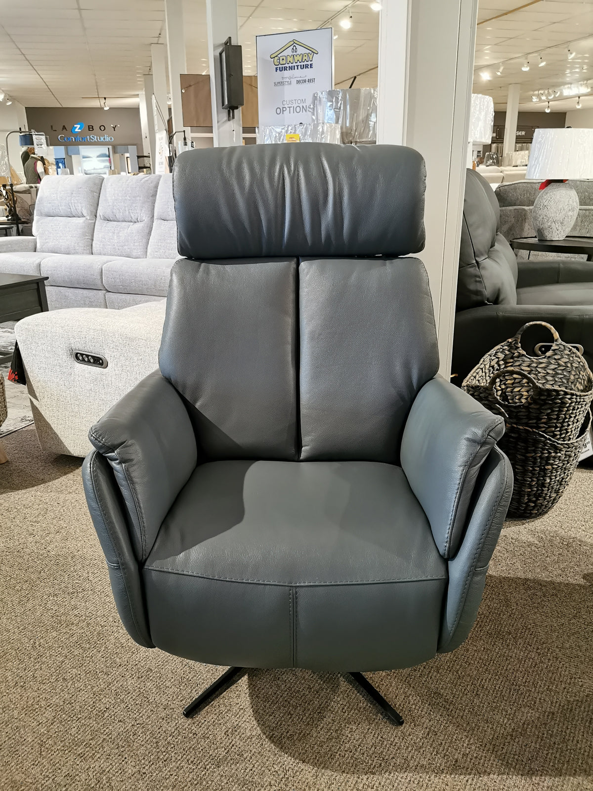 The Argo Power Recliner by Donald Choi, featuring a luxurious black Italian leather finish, a headrest, and a motion mechanism, is on display in the furniture store showroom.