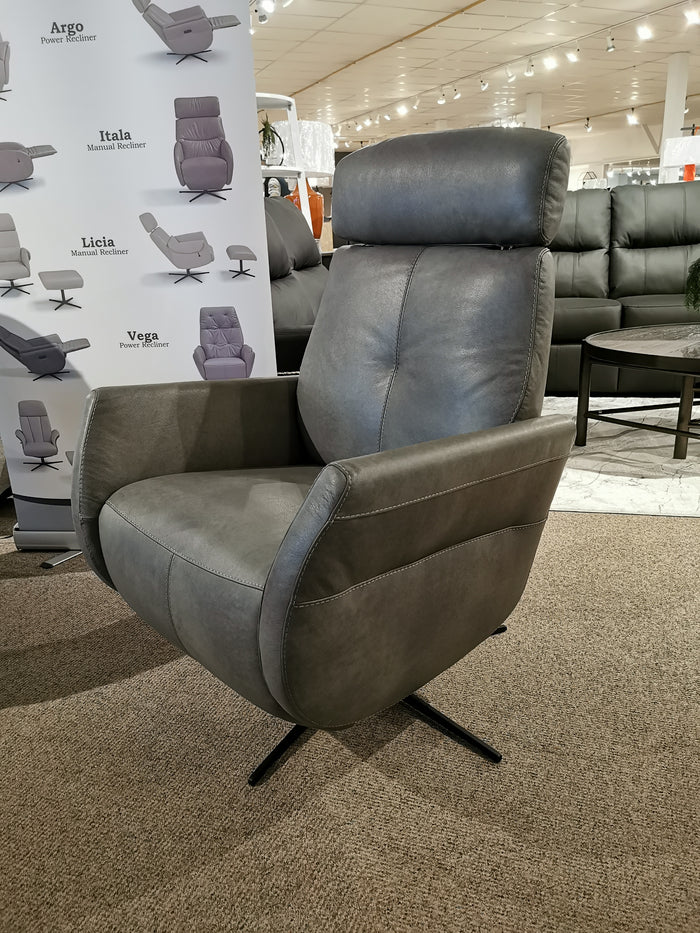 Donald Choi's Artu Power Recliner, crafted in gray Italian leather and featuring a headrest, is showcased in a showroom with posters and additional seating visible in the background.