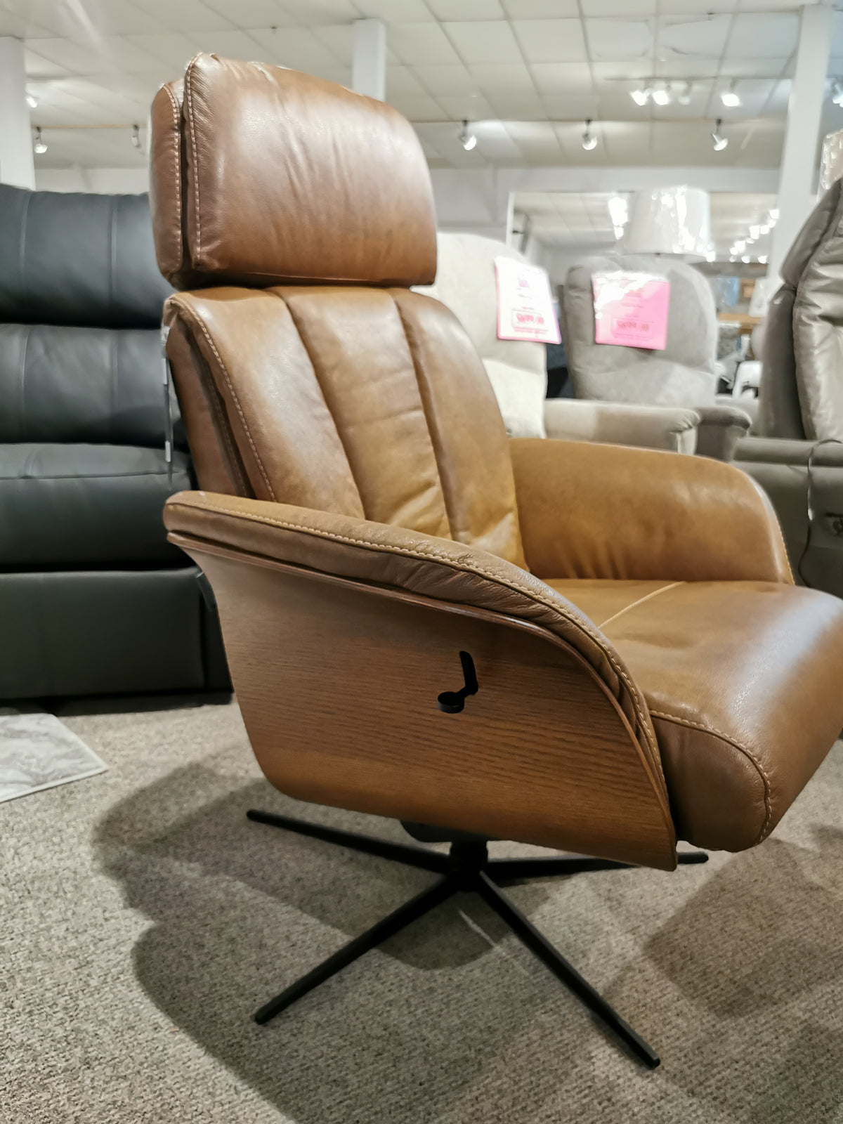 In a showroom filled with elegant chairs, the Vilma Recliner with Ottoman from Donald Choi stands out, crafted from exquisite Italian leather and featuring a cutting-edge Motion Italia mechanism for seamless reclining.