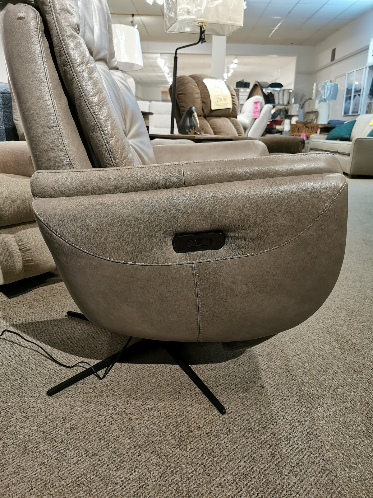 Side view of the Vega Power Recliner by Donald Choi in a showroom, crafted from premium Italian leather with high-density foam for unmatched comfort. It features a control button on the side and is set against a carpeted floor.