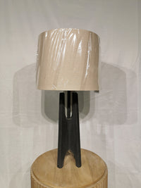 The Crestview Collection Alterna Table Lamp with a beige shade sits on a wooden table against a white background.