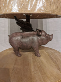 The Crestview Collection's Hogs Fly Table Lamp features a whimsical winged pig statue on a wooden base.