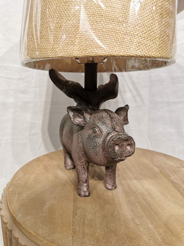 The Crestview Collection Hogs Fly Table Lamp offers southern-chic charm with a whimsical pig design and burlap-style shade.