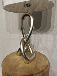 The Crestview Collection ST. James Table Lamp features a twisted silver finish and white shade on a wooden table.