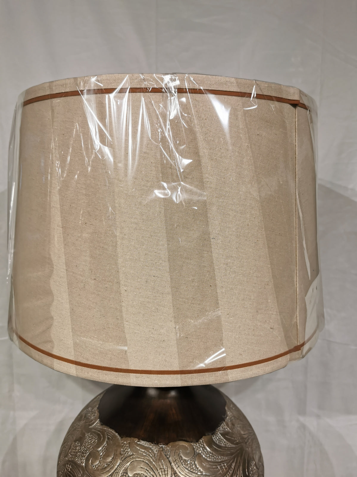 A Crestview Collection Silver Canyon Table Lamp with a natural linen shade is set against a plain white background.