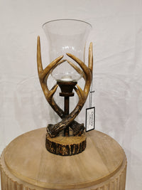 The Crestview Collection Huxley Antler Table Lamp decorates a rustic round wooden table.