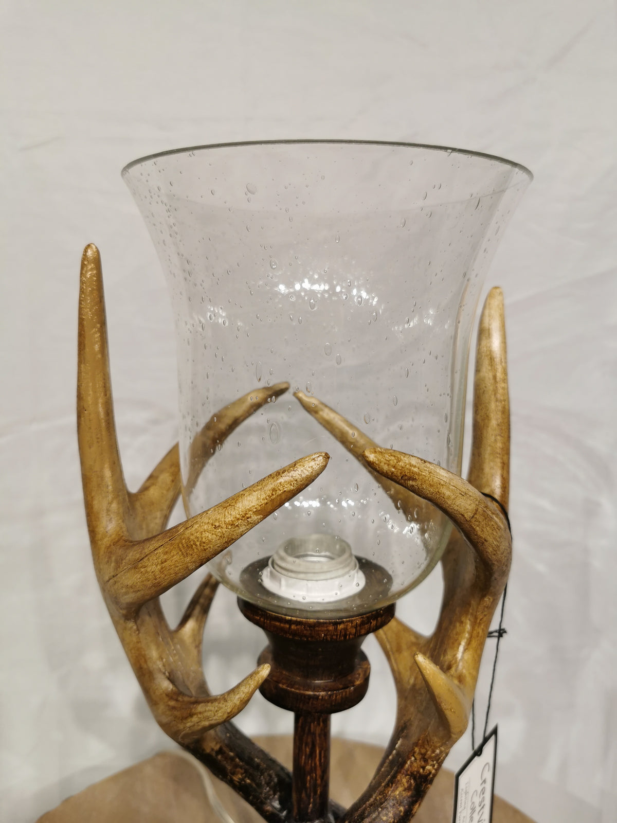 The Crestview Collection's Huxley Antler Table Lamp has a glass holder and rustic deer antler-style base on wood.