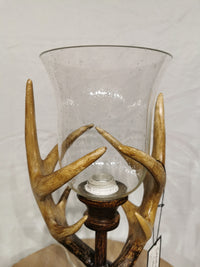 The Crestview Collection's Huxley Antler Table Lamp has a glass holder and rustic deer antler-style base on wood.