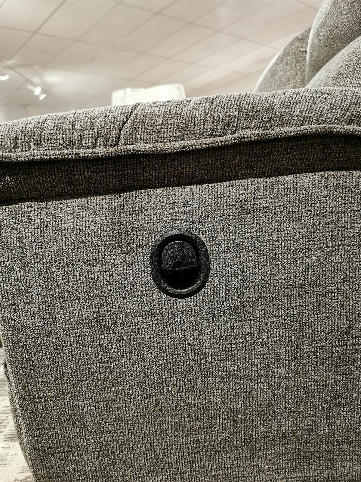 Close-up of the 706 Jay Loveseat by La-z-boy in gray, featuring a round black power outlet for personalized reclining.