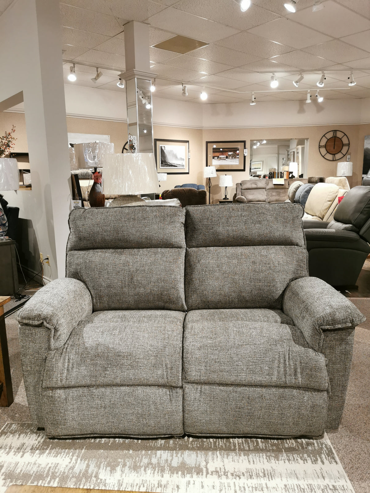 The 706 Jay Loveseat by La-z-boy is a gray two-seater offering personalized reclining, styled with lamps and wall art.