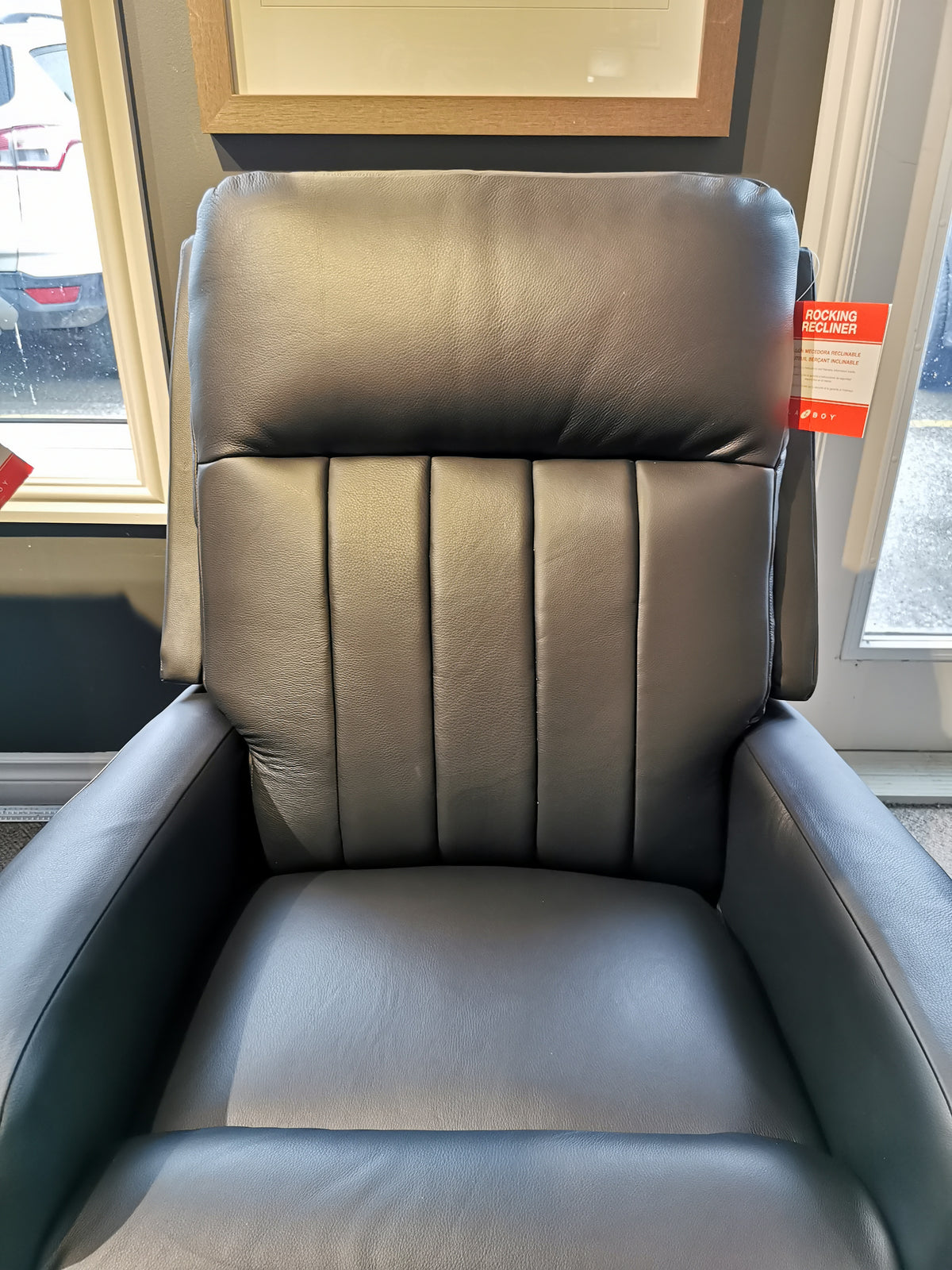 La-z-boy's 747-10 Finley Black Leather Rocker Recliner with ultra-plush chaise seat is displayed in a store by a window.