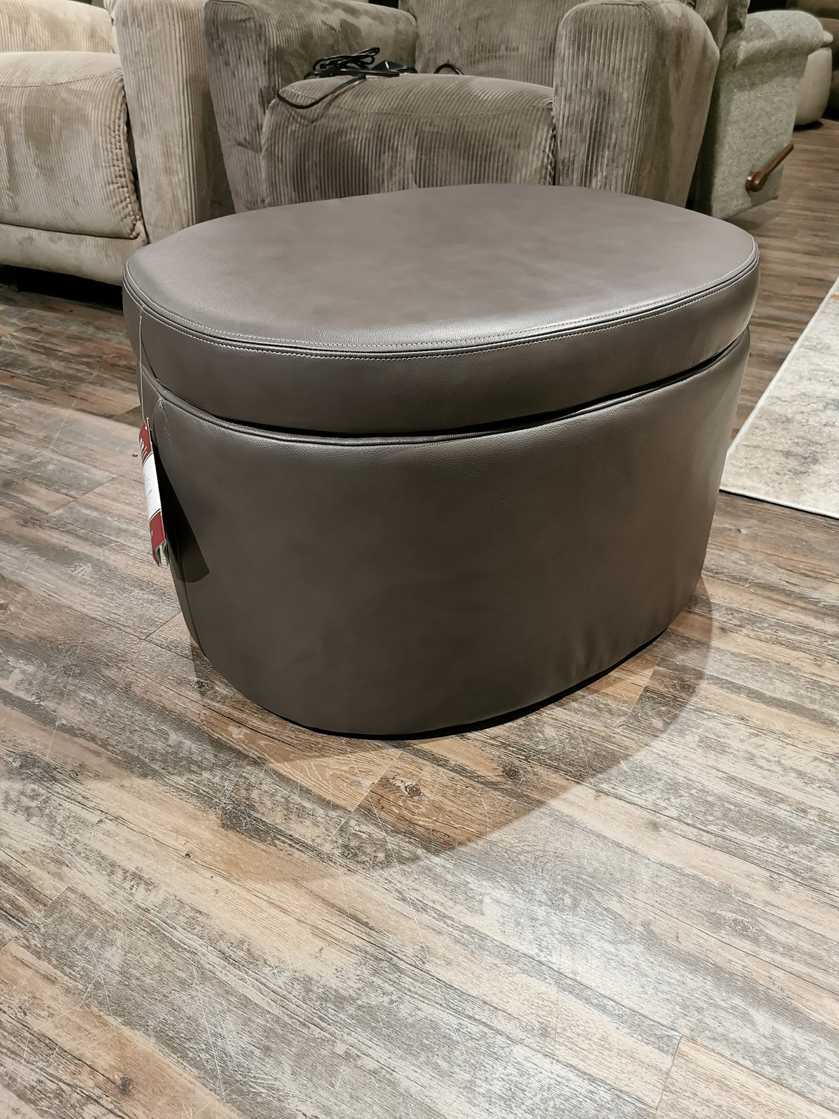 The La-z-boy Maeve 402 Storage Ottoman, with a storage nook and hidden casters, is in the living room on a wooden floor.