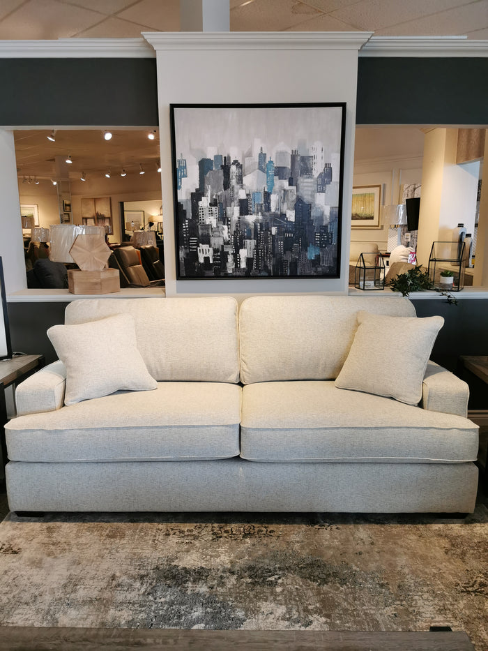 A La-Z-Boy 663 Paxton Sofa sits in front of a cityscape painting in a well-lit furniture showroom.