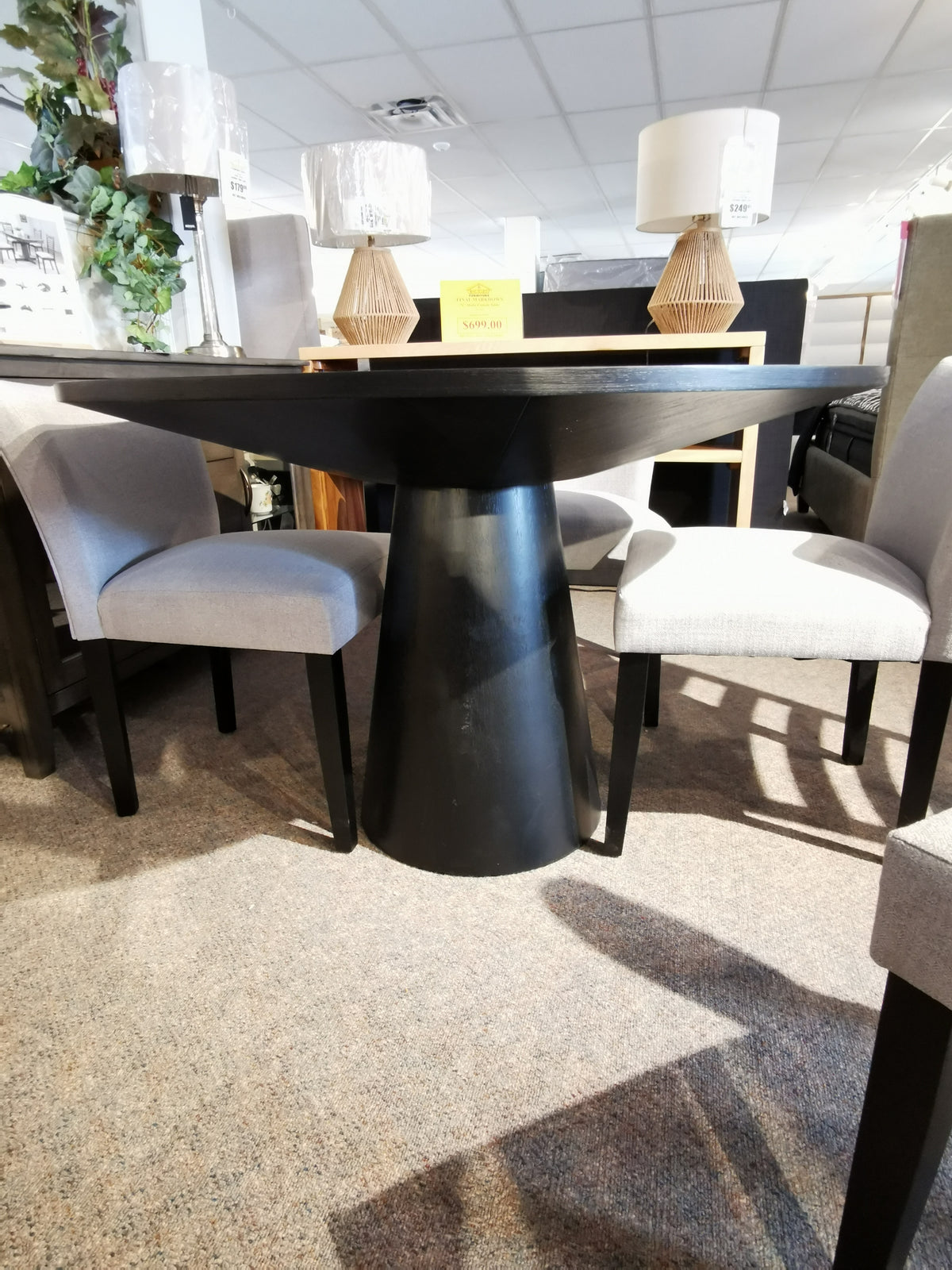 The Rory 48" Dining Package by Donald Choi features a black oak veneer table with gray chairs in the showroom.