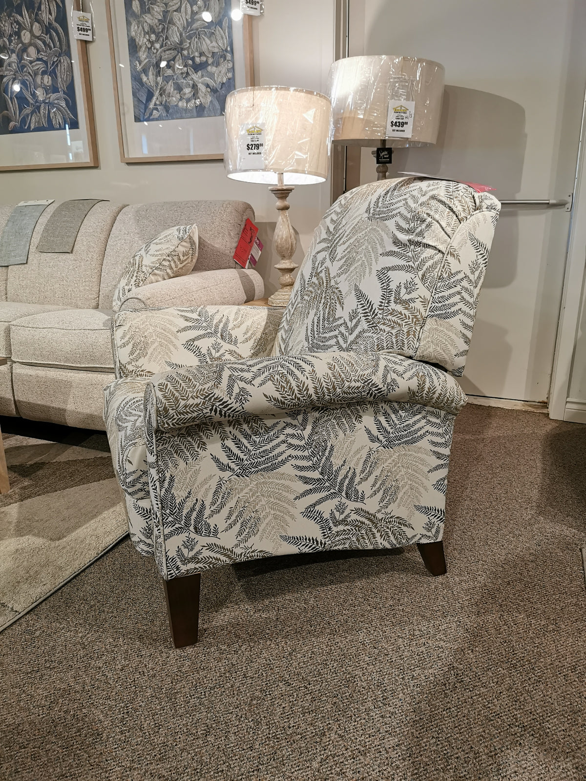 La-Z-Boy 424 Fletcher Power Hi-Leg Recliner, with leaf pattern, next to beige sofa and lamp in a furniture store.