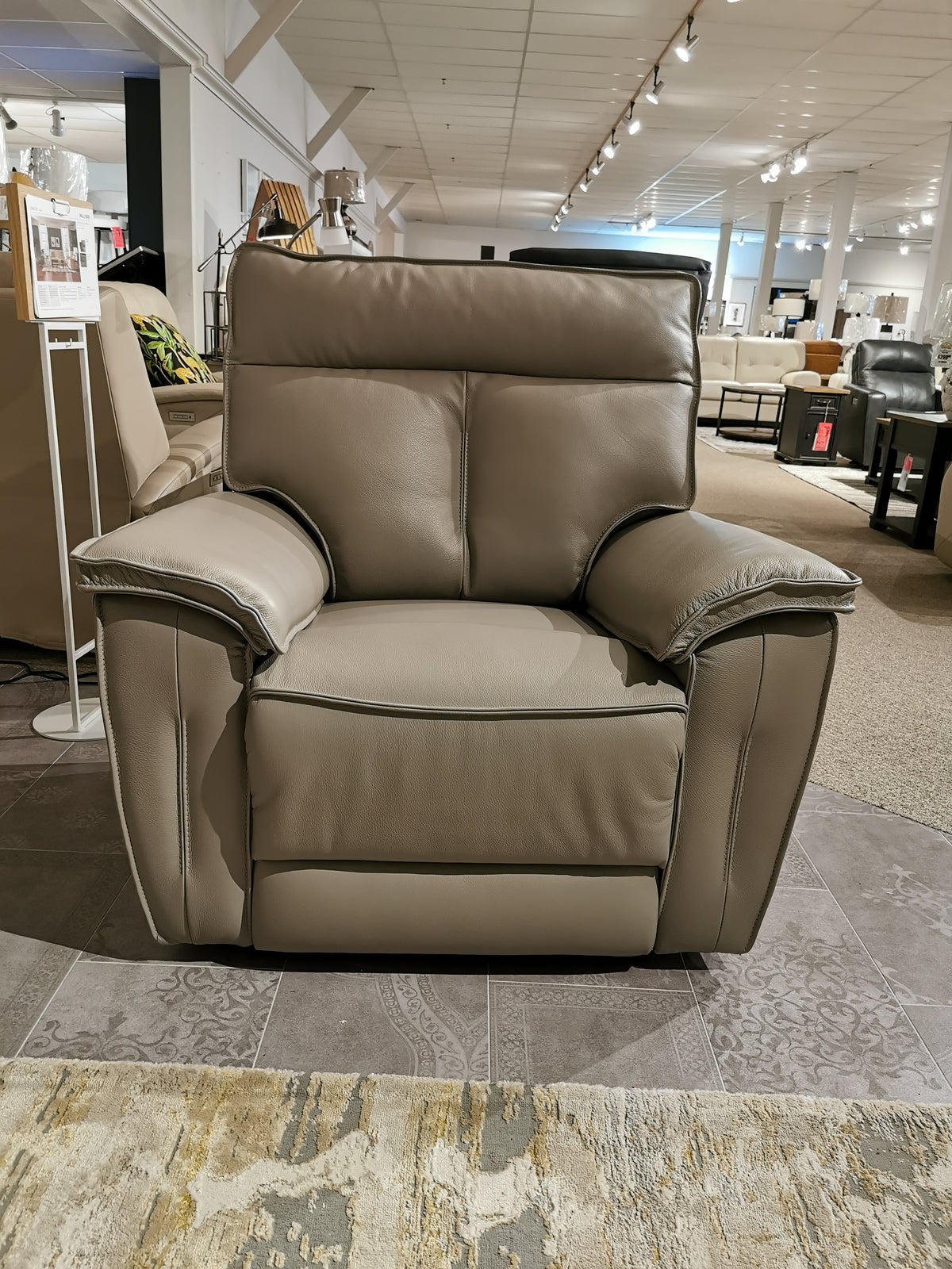 The showroom features the 41187 Oakley Zero Gravity Power Recliner by Palliser, a large gray leather armchair.