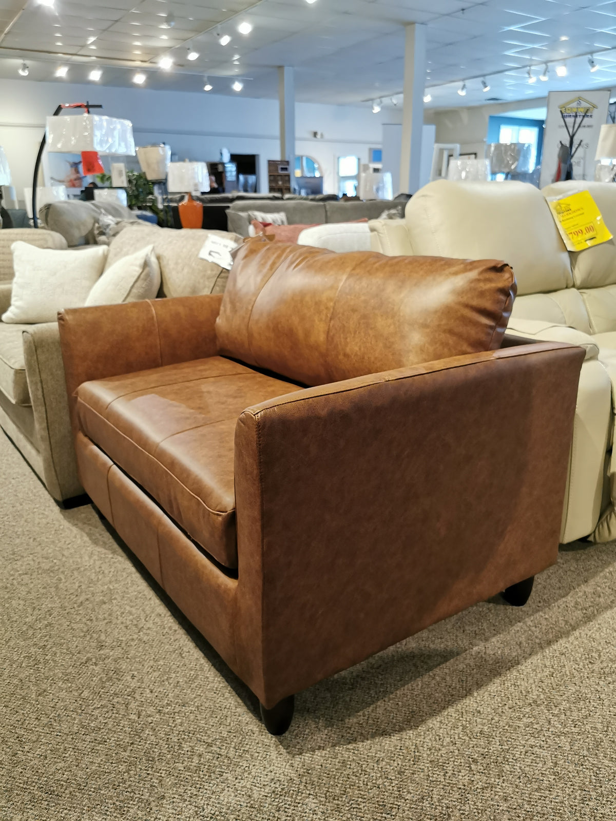 The Bayment Chair Sofa Bed by Best on display with a memory foam mattress among other couches in the store.