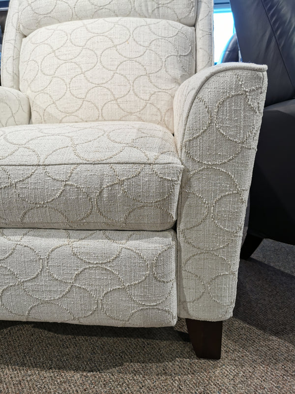 Close-up of a 458 Rheeves Hi-Leg Recliner by La-Z-Boy with circular upholstery and wood legs, next to a dark sofa.