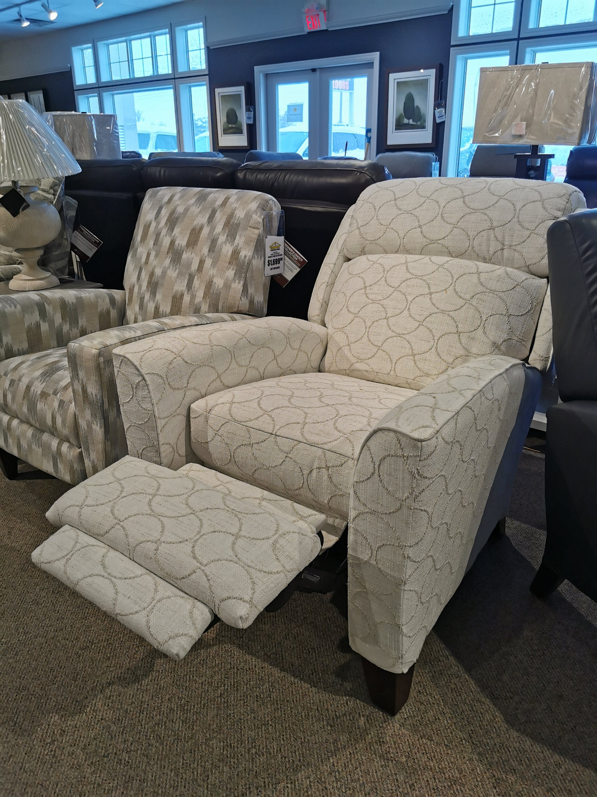 Two La-Z-Boy 458 Rheeves Hi-Leg Recliners, with decorative legs, are showcased in a furniture store.