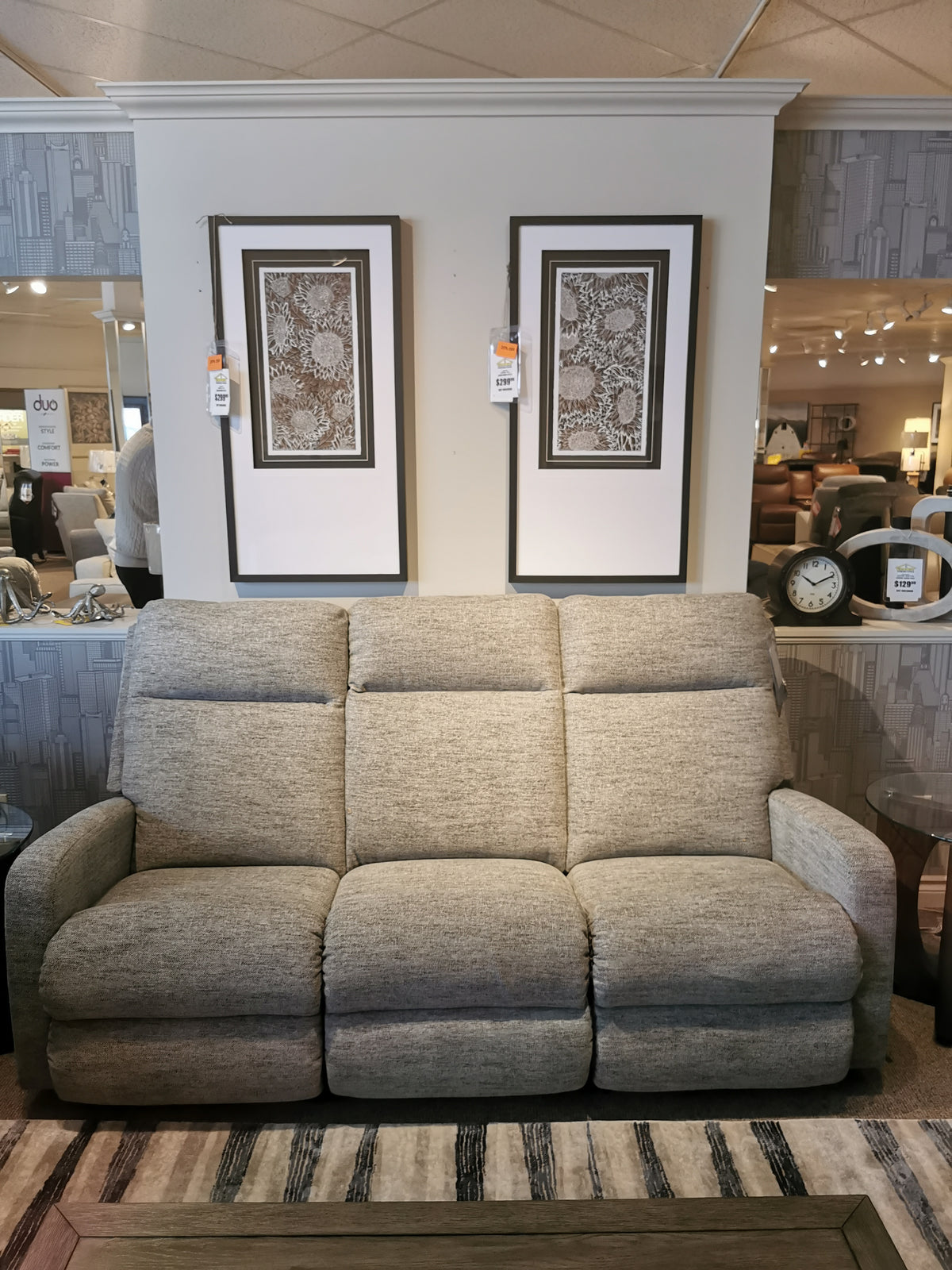 La-z-boy's 747 Finley Reclining Sofa in gray, surrounded by two framed artworks, enhances the showroom.