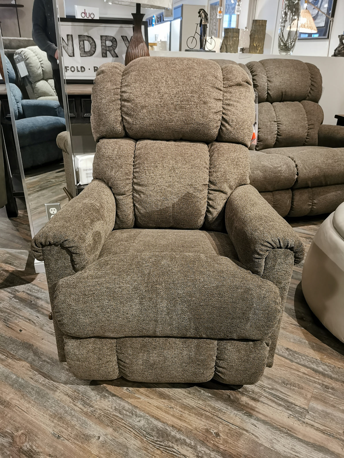 A brown La-Z-Boy 512 Pinnacle Rocker Recliner adds plush comfort to a showroom with wooden flooring.