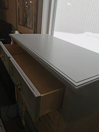 The Bonanza Grey Chest by Vaughan Bassett with an open top drawer is placed by a window.