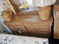 771 Vista 8 Drawer Dresser by Vaughan Bassett with mirror and two woven lamps next to bed with patterned mattress.