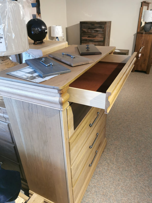 A Vaughan Bassett 771 Vista 5 Drawer Chest with an open drawer and brochures on top in a showroom.