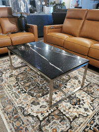 Modern living room with brown leather sofas, a Magnussen T5760 Kira Cocktail Table on a patterned rug.