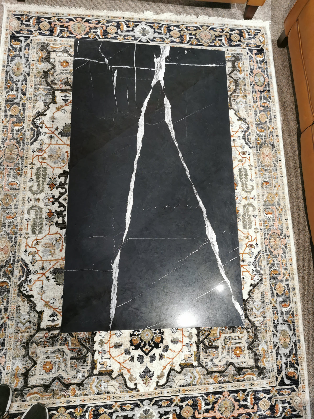 A T5760 Kira Cocktail Table by Magnussen, black marble with white veining, rests on a patterned rug.