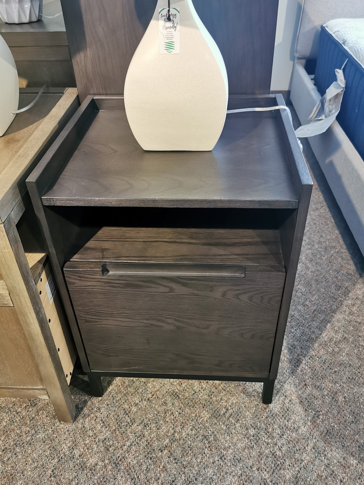 Donald Choi's Hanson Charcoal Nightstand with a drawer and white vase on carpet.