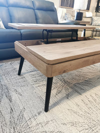 Fletcher Cocktail Table by Magnussen, with a lift-top and driftwood finish, adds contemporary charm on a patterned rug.