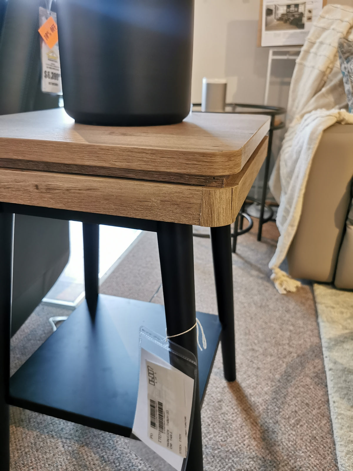 The Magnussen T5864 Fletcher End Table features driftwood with black metal legs, enhanced by a black pot atop.