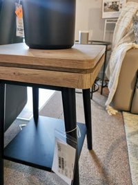 The Magnussen T5864 Fletcher End Table features driftwood with black metal legs, enhanced by a black pot atop.