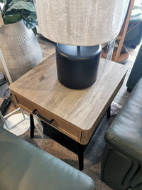 The Magnussen Fletcher End Table (T5864) with a black lamp adds charm between green leather furniture and a large vase.